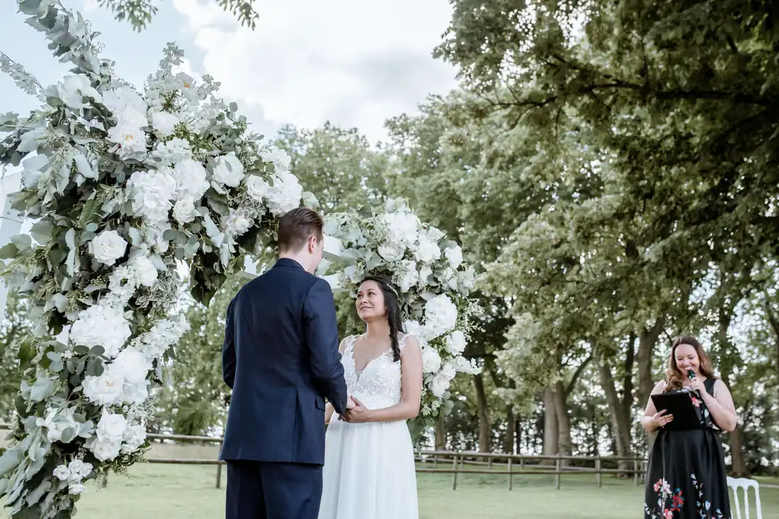 Wedding ceremony in front of a white floral arch